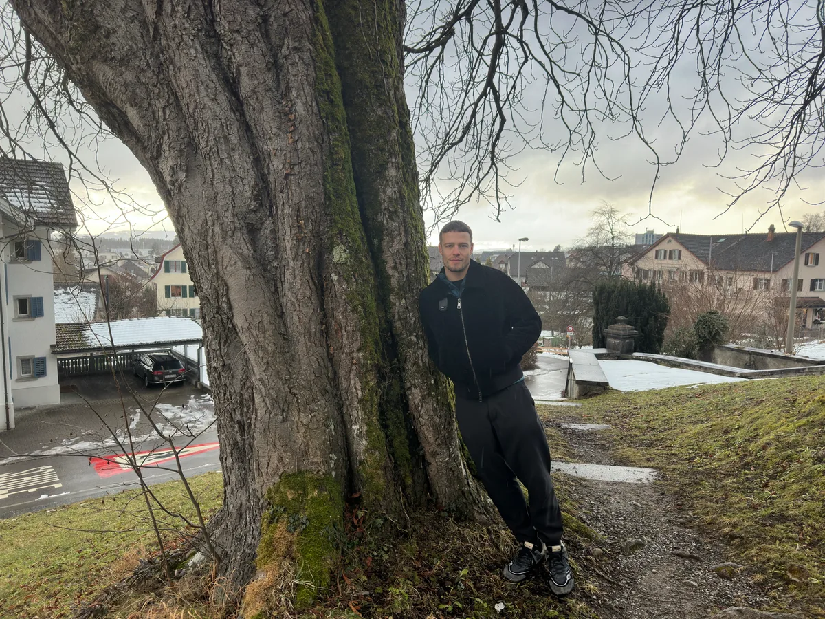 Ein Mann lehnt sich an einen Baum an.